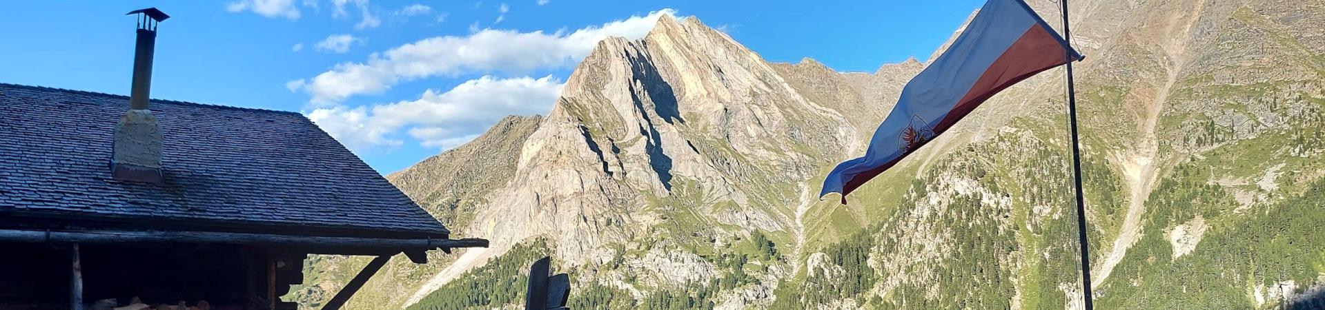 Rifugio+alpino+con+bandiera+issata+e+montagna+sullo+sfondo